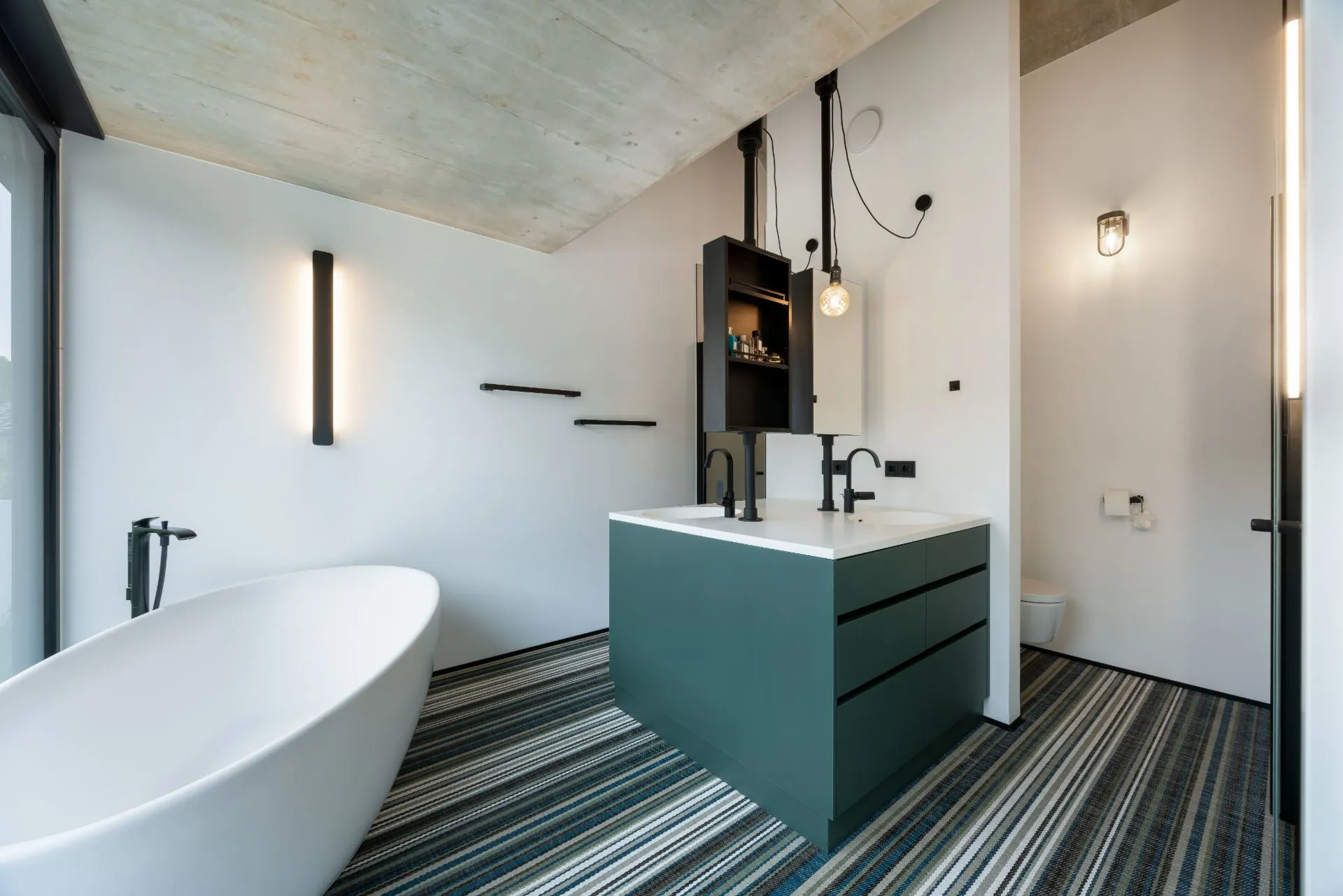 Modernes Bad mit freistehender Badewanne, Doppelwaschtisch und gestreiftem Boden.