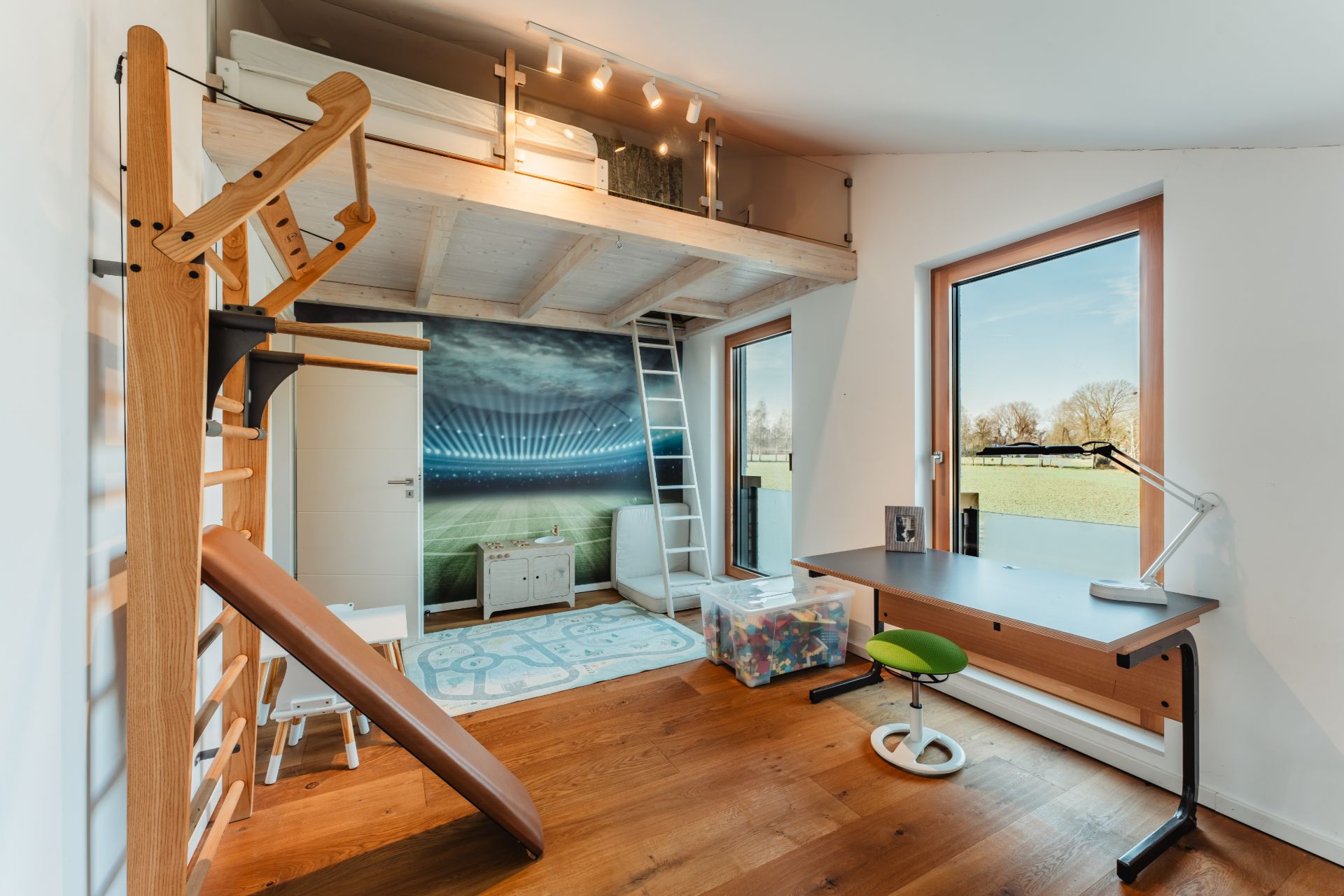 Kinderzimmer mit Hochbett, Kletterwand, Rutsche, Schreibtisch und großem Fenster mit Ausblick.