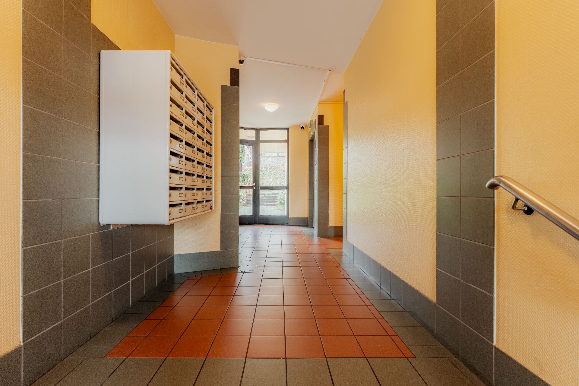 Heller Hausflur mit Briefkästen an der Wand und Kachelfußboden.