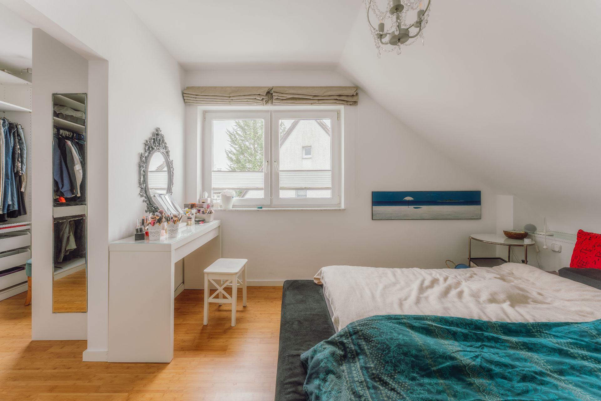 Helles Schlafzimmer mit Bett, Schminktisch, Spiegel und offenem Kleiderschrank.