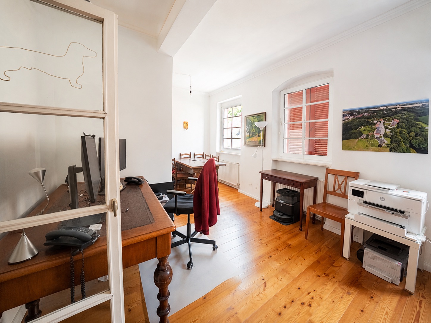 Helles Arbeitszimmer mit Holzboden, Schreibtischen, Stühlen und Computern.