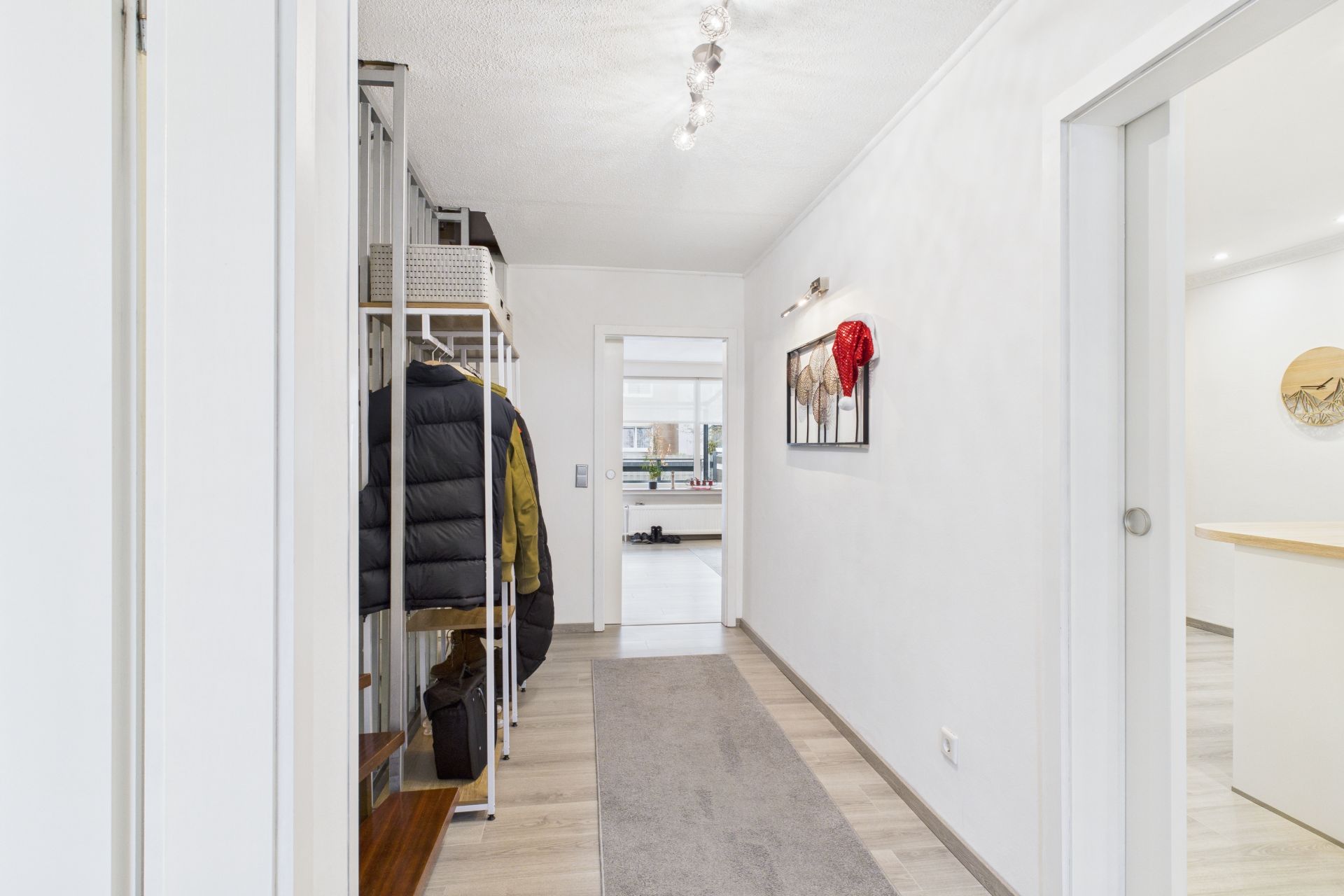 Heller Flur mit Garderobe, Teppich und Blick in einen Wohnraum.