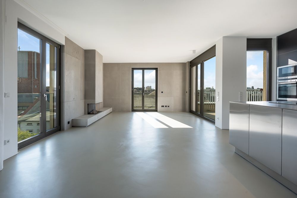 Helles, modernes Wohnzimmer mit großen Fenstern und offener Küche.