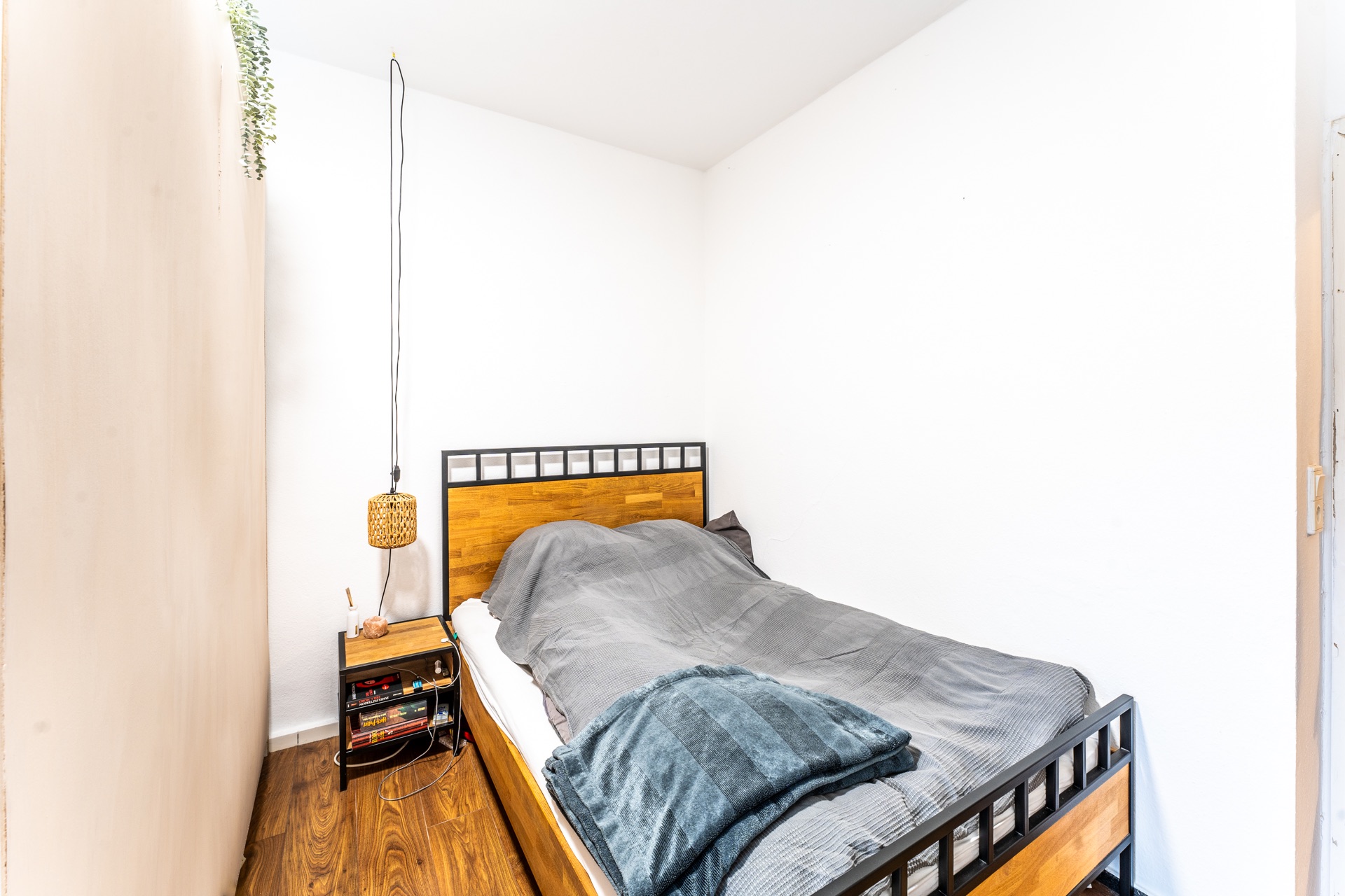 Kleines Schlafzimmer mit Einzelbett, Nachttisch und Holzboden.