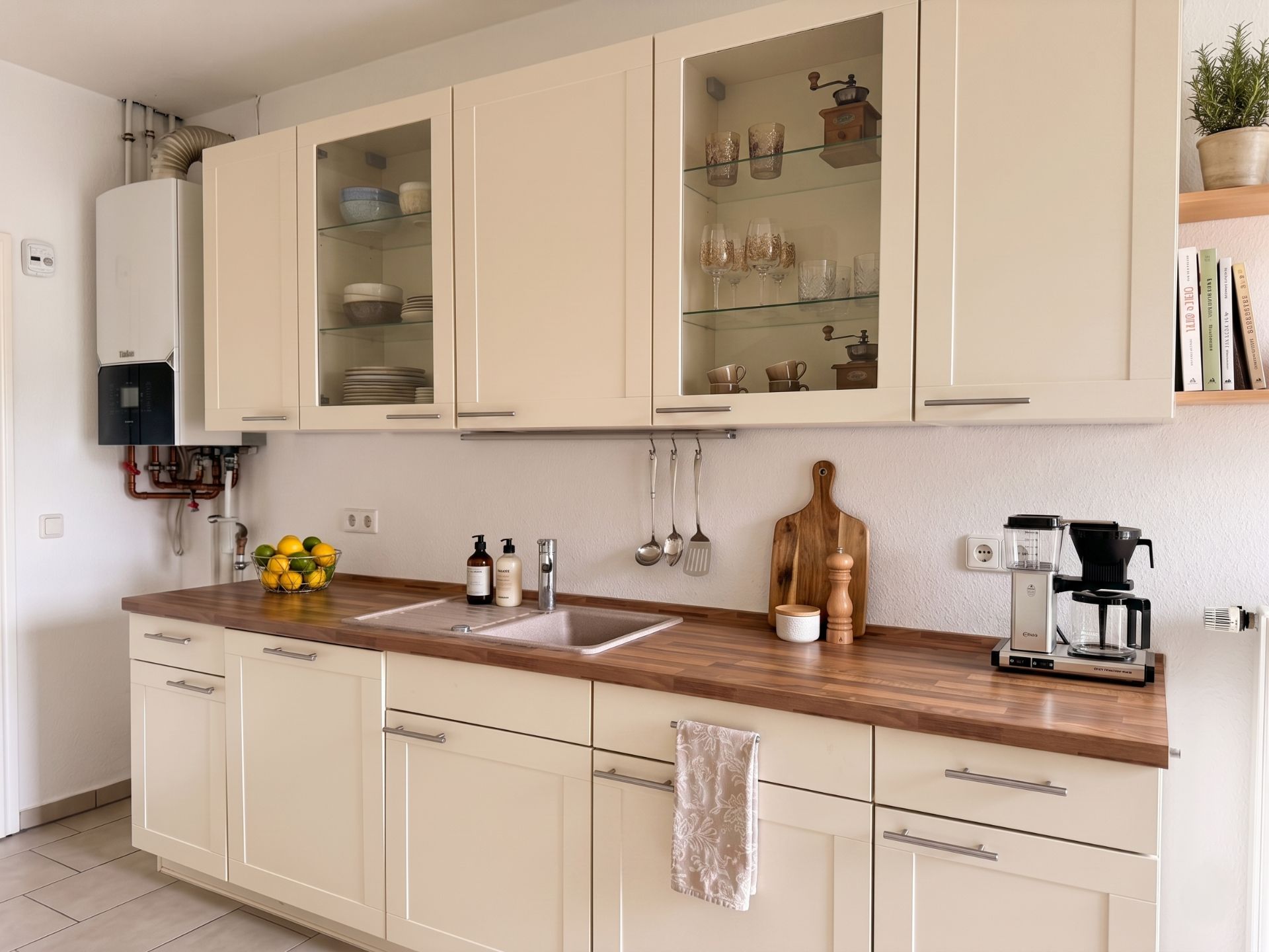 Moderne Küche mit Holzarbeitplatte, Spüle, Hängeschränken und Kaffeemaschine.