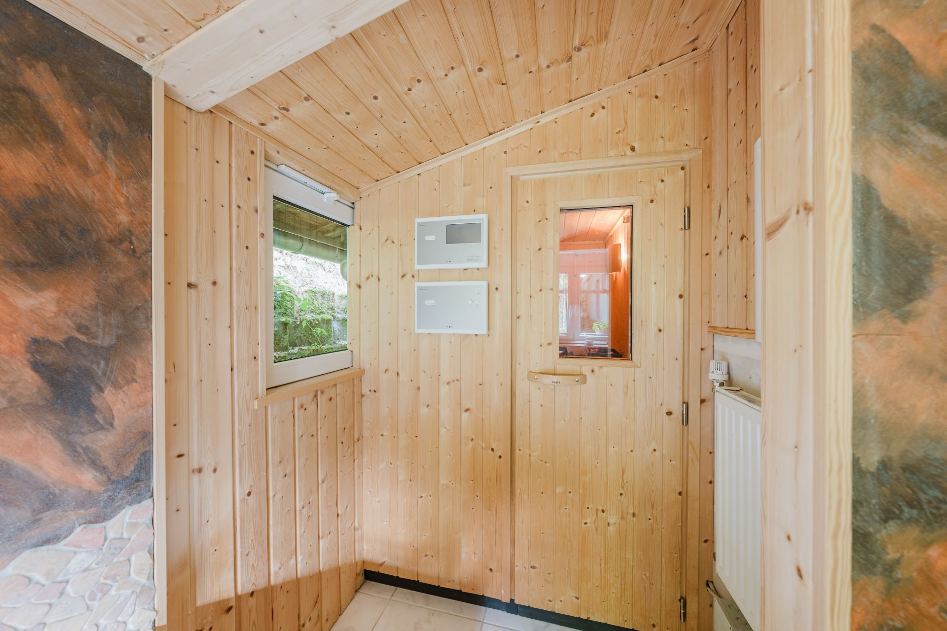 Kleiner Raum mit Holzverkleidung, Fenster und Tür mit Glaseinsatz.