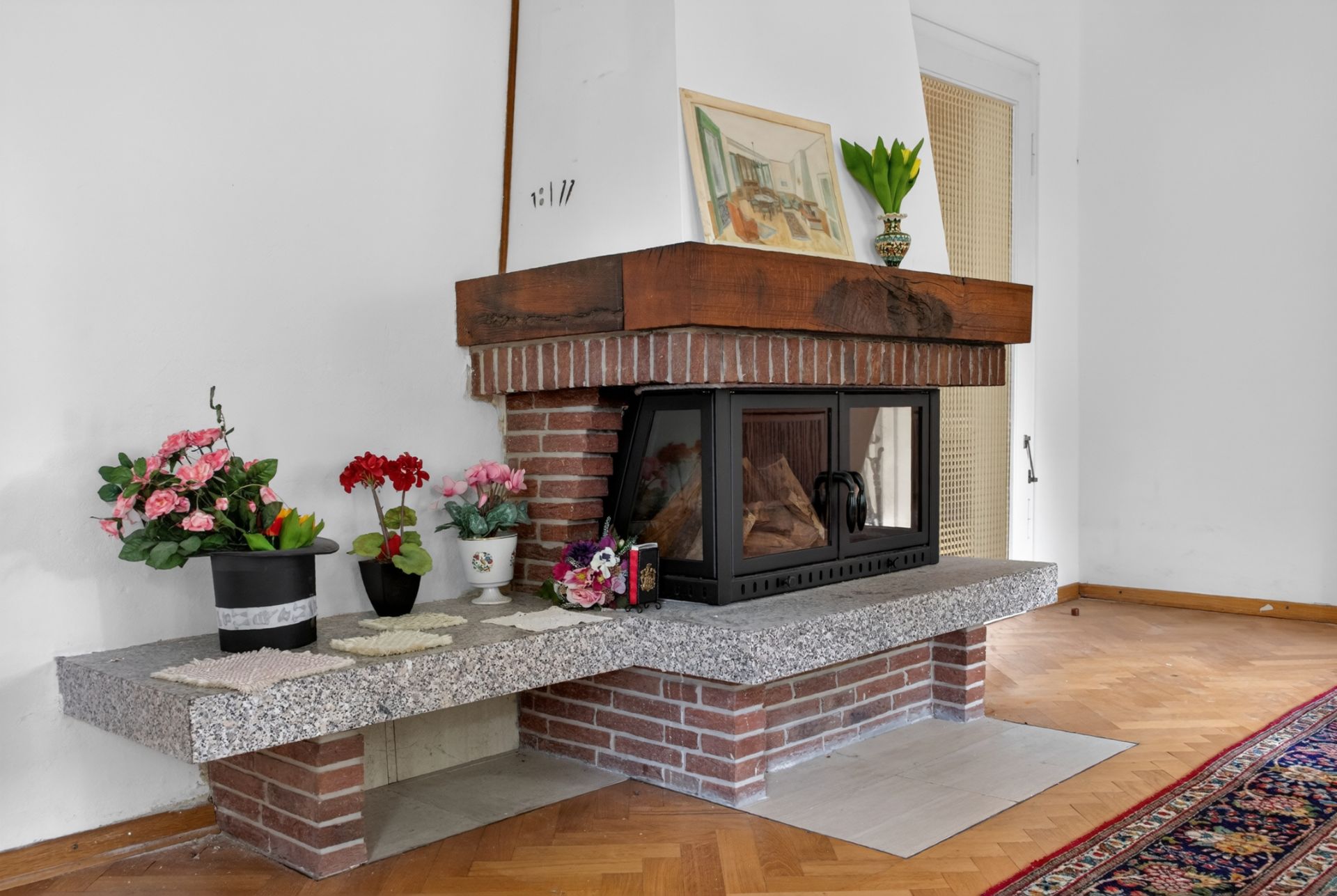 Ecke mit gemauertem Kamin, Blumen und Dekoration auf Marmorbank in einem Wohnzimmer.
