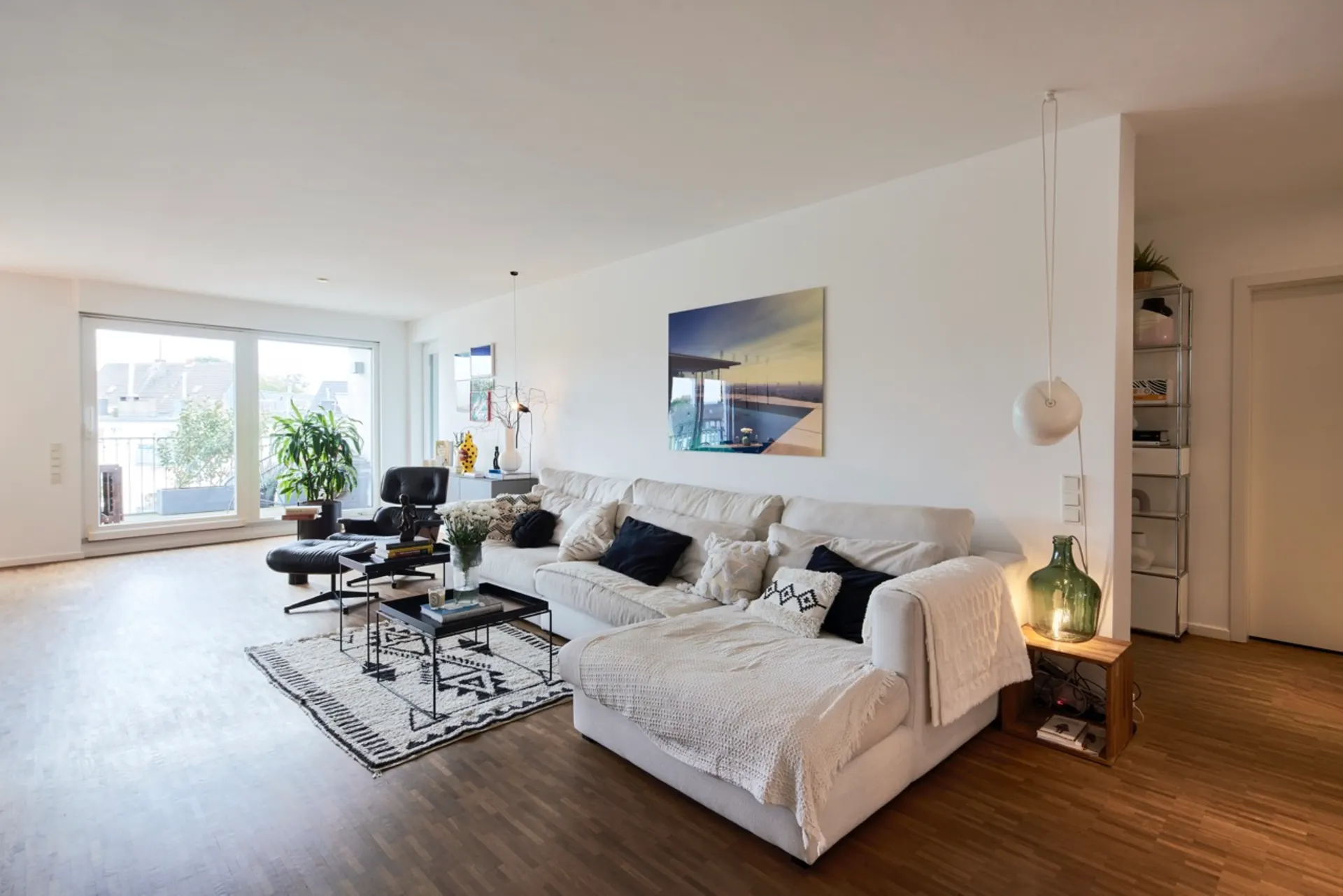 Modernes Wohnzimmer mit großem Sofa, Couchtisch, Pflanzen und großem Fenster.