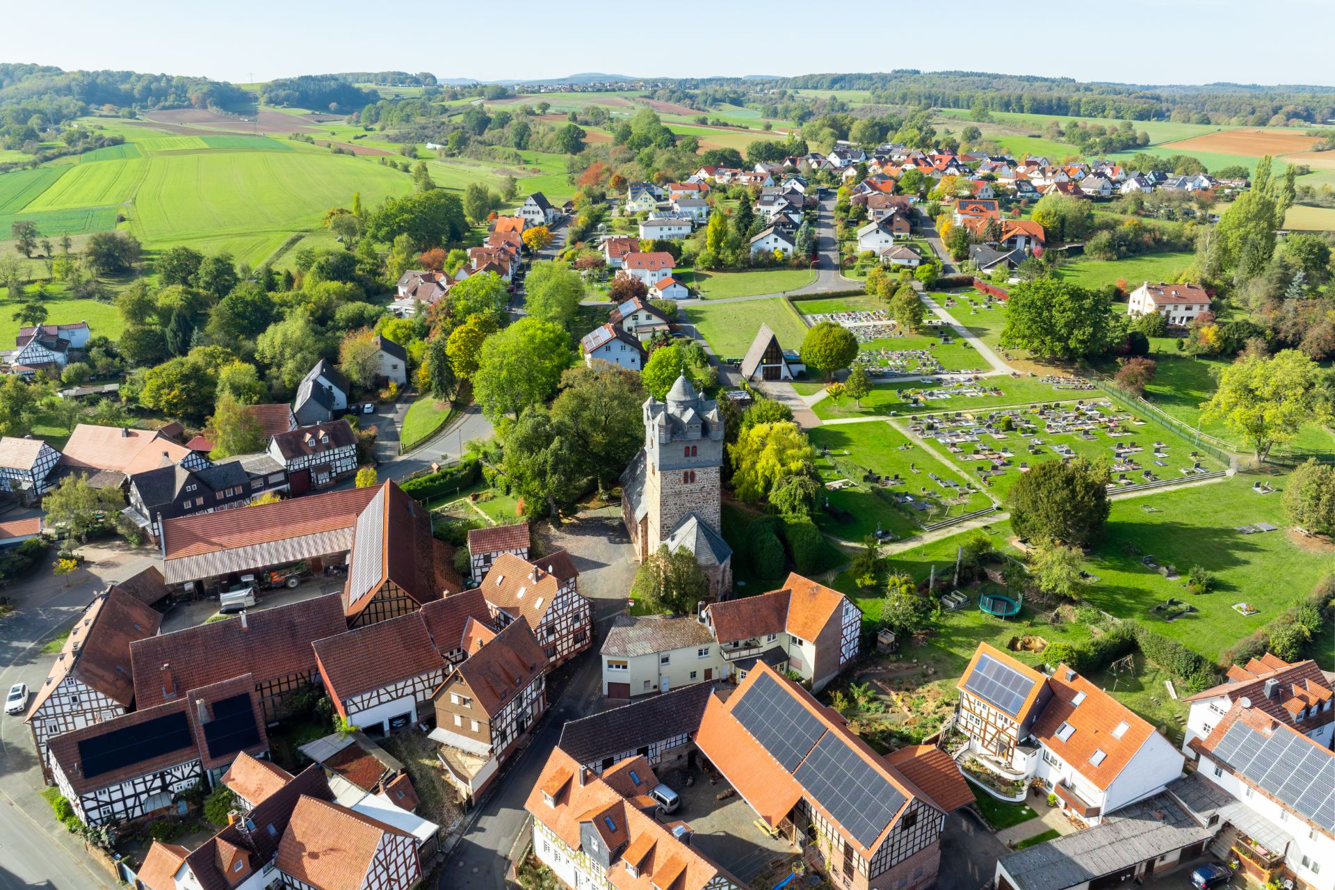 Luftaufnahme eines Dorfes mit Fachwerkhäusern, Kirche und umliegenden Feldern.