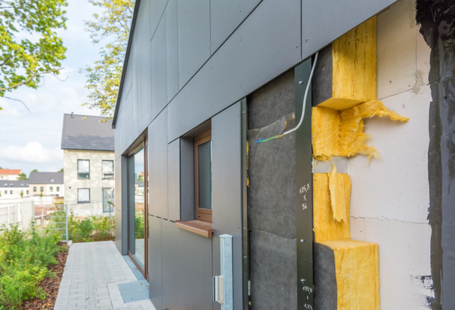 Fassade eines Hauses mit sichtbarer Wärmedämmung und geöffnetem Wandbereich.