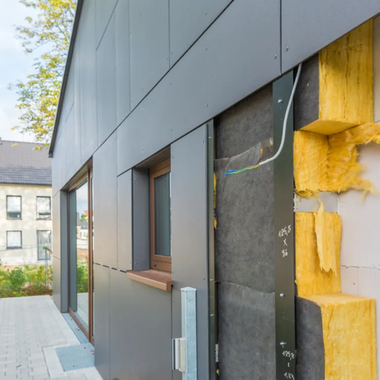 Fassade eines Hauses mit sichtbarer Wärmedämmung und geöffnetem Wandbereich.
