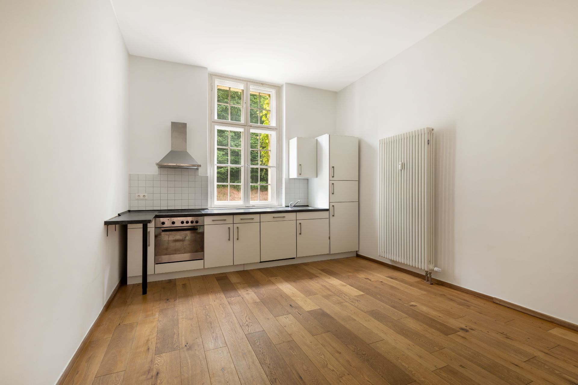 Helle Einbauküche mit weißem Schrank, Holzfußboden und großem Fenster.
