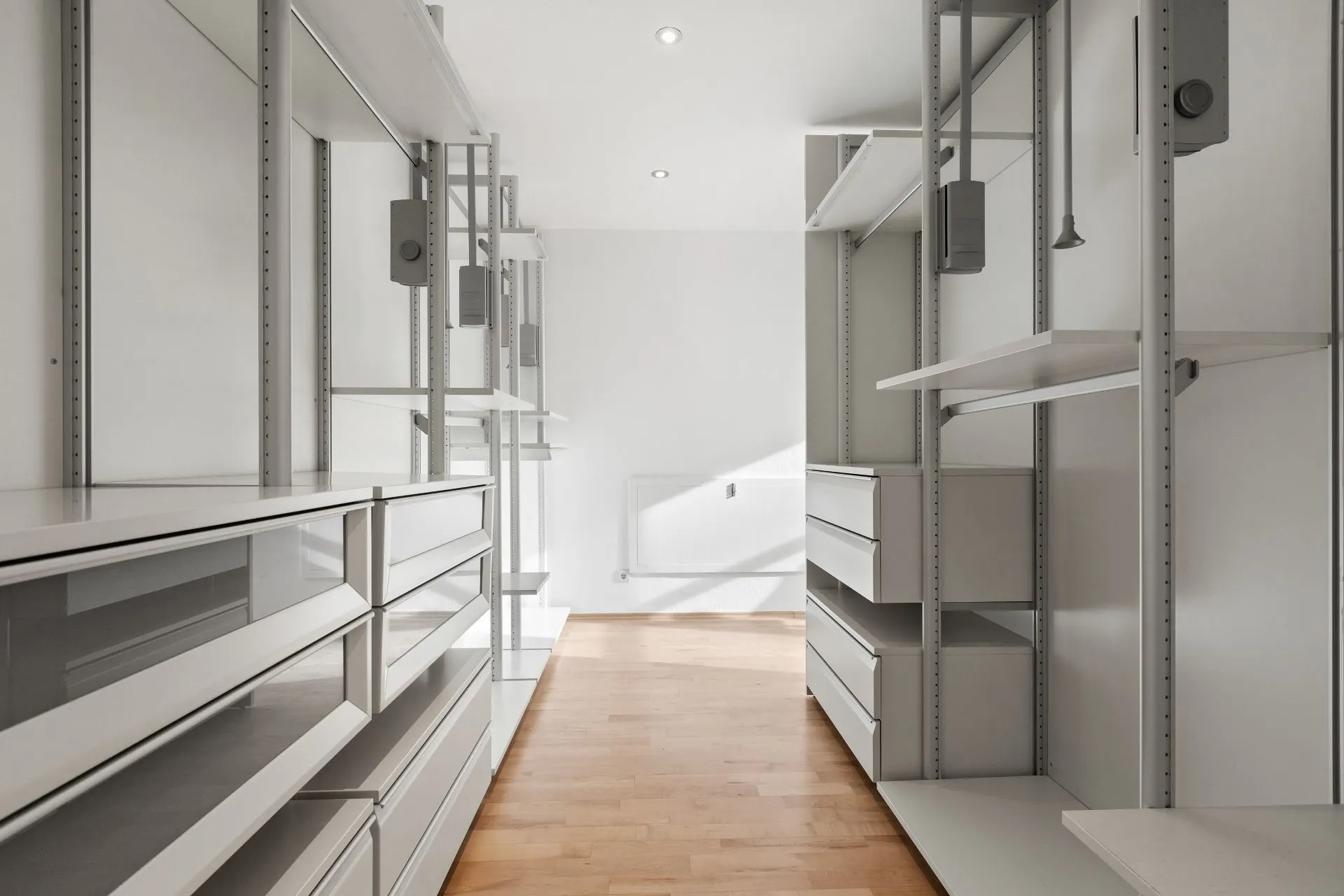 Moderner begehbarer Kleiderschrank mit offenen Regalen und Schubladen, Holzboden.