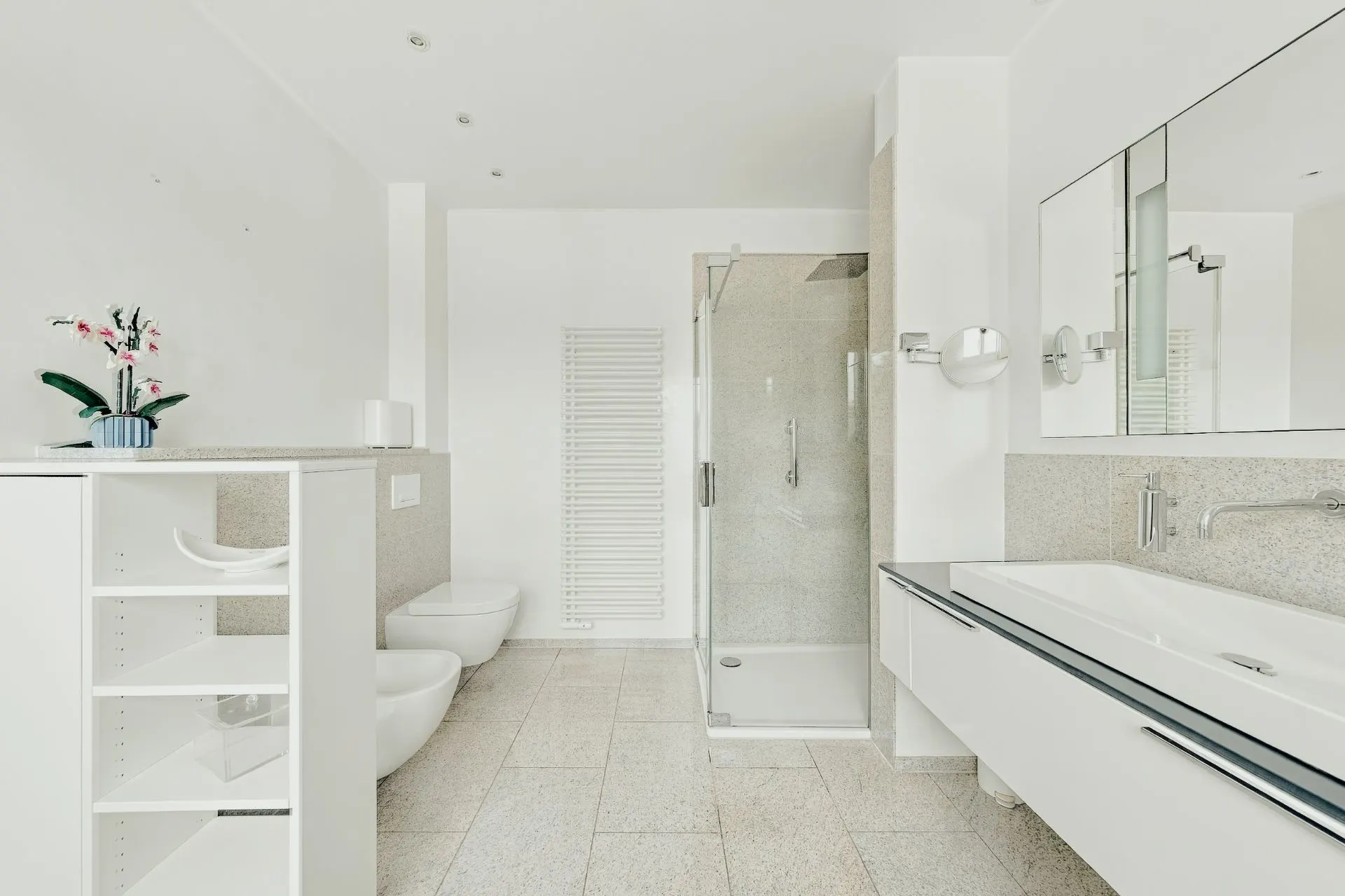 Modernes Bad mit Dusche, Doppelwaschbecken, WC, Bidet, Regal und Spiegel.