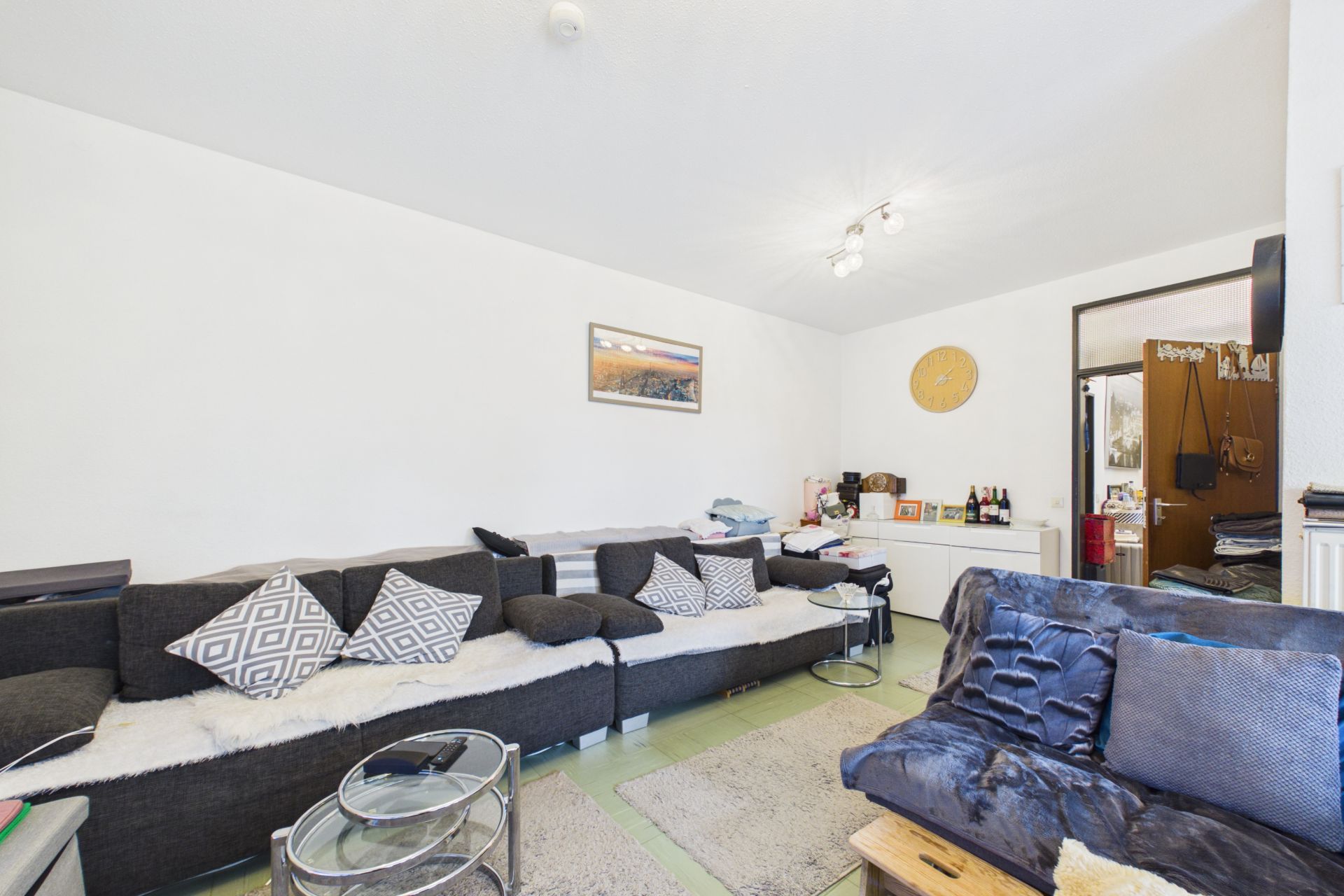 Wohnzimmer mit zwei Sofas, Couchtischen, Teppichen und hellen Wänden.