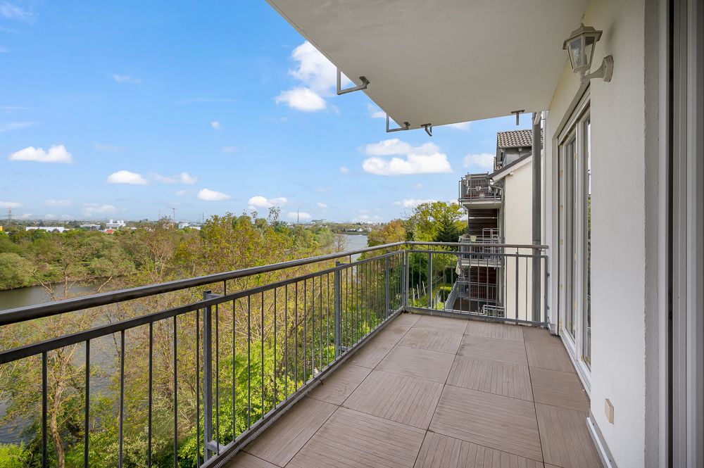 Geräumiger Balkon mit Fliesenboden und Blick auf Fluss und Bäume.