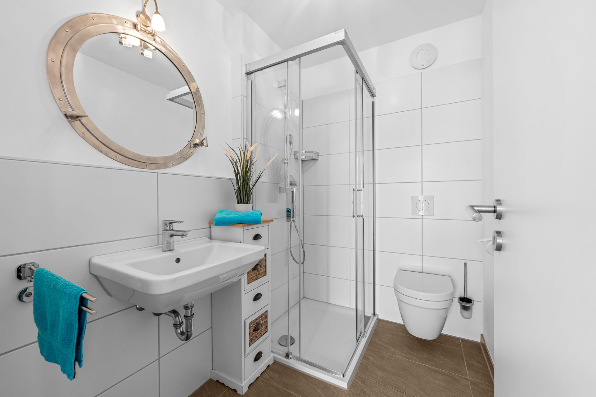 Modernes Badezimmer mit Dusche, Waschbecken, Spiegel und WC, weiße Fliesen, brauner Boden.