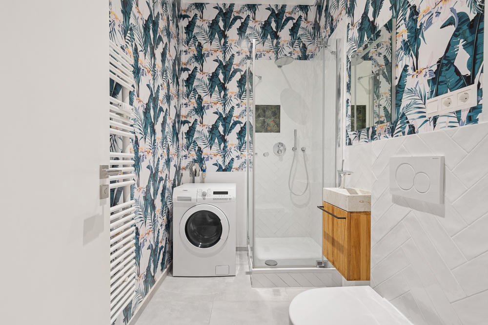 Modernes Bad mit Waschmaschine, Dusche, Holzwaschbecken und gemusterter Tapete.