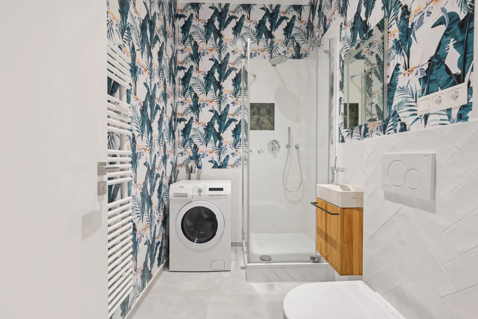 Modernes Bad mit Waschmaschine, Dusche, Holzwaschbecken und gemusterter Tapete.