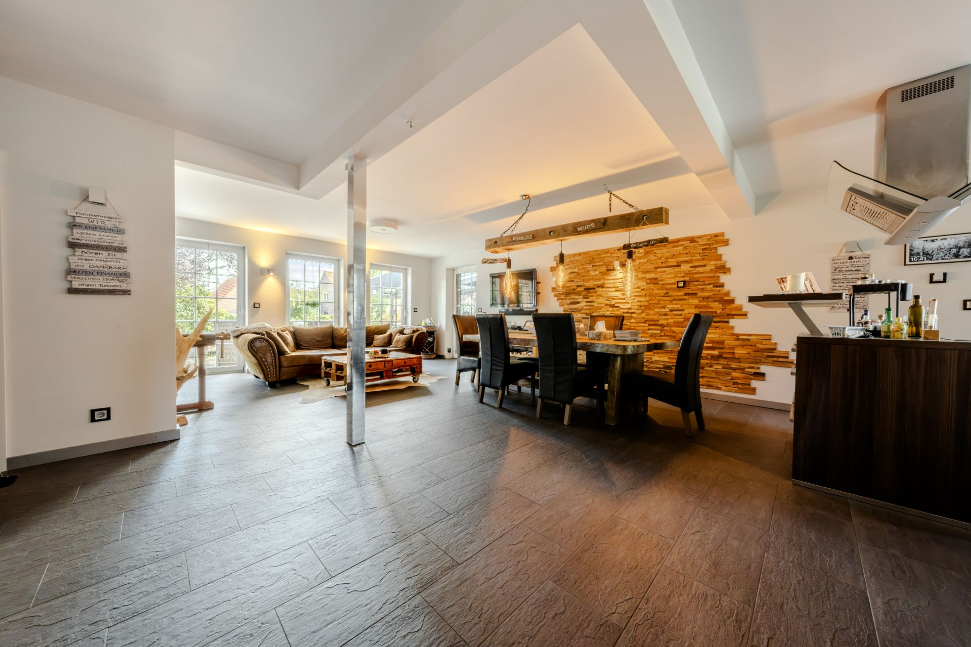Geräumiges Wohnzimmer mit Essbereich, großen Fenstern, Sofa, Esstisch und moderner Dekoration.