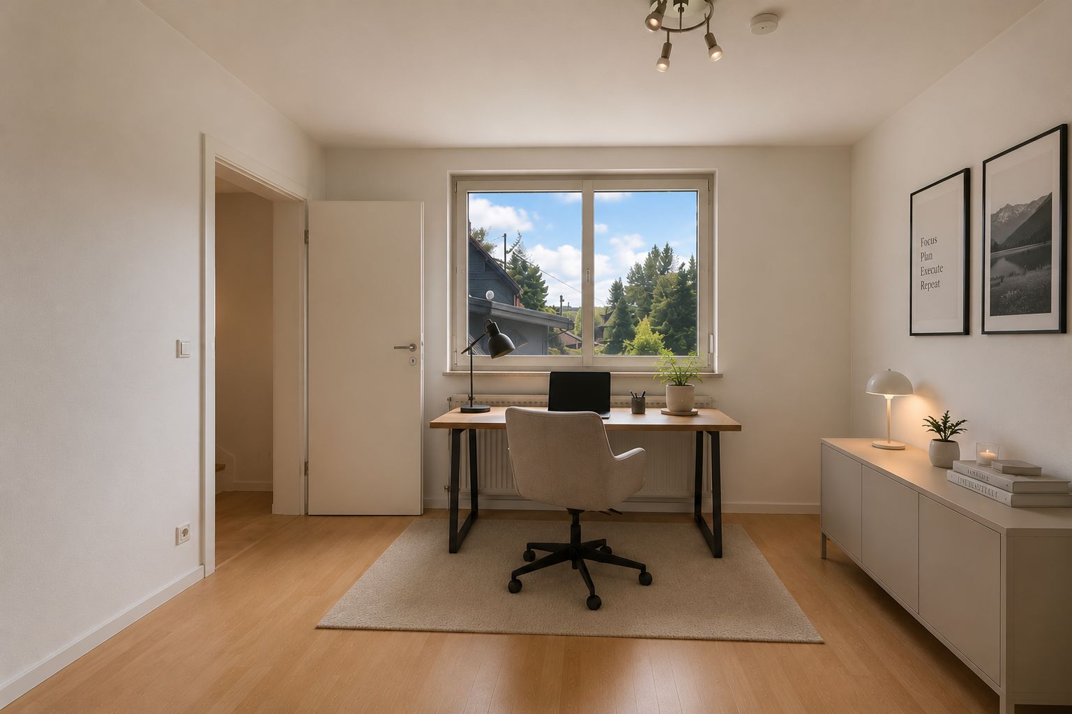 Helles Arbeitszimmer mit Schreibtisch, Stuhl und Fenster mit Blick ins Grüne.