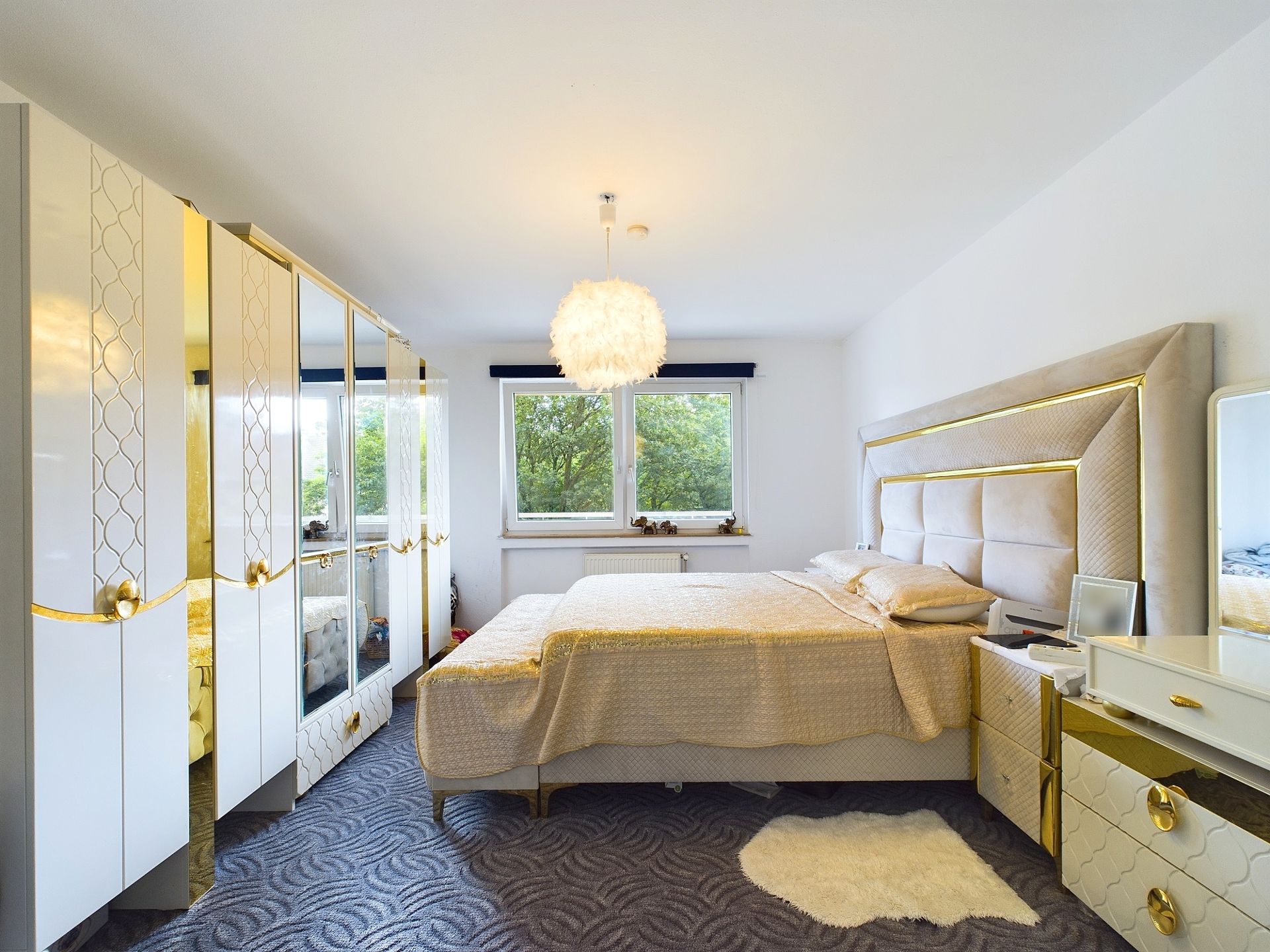 Modernes Schlafzimmer mit großem Bett, Kleiderschränken, Fenster und Teppich.