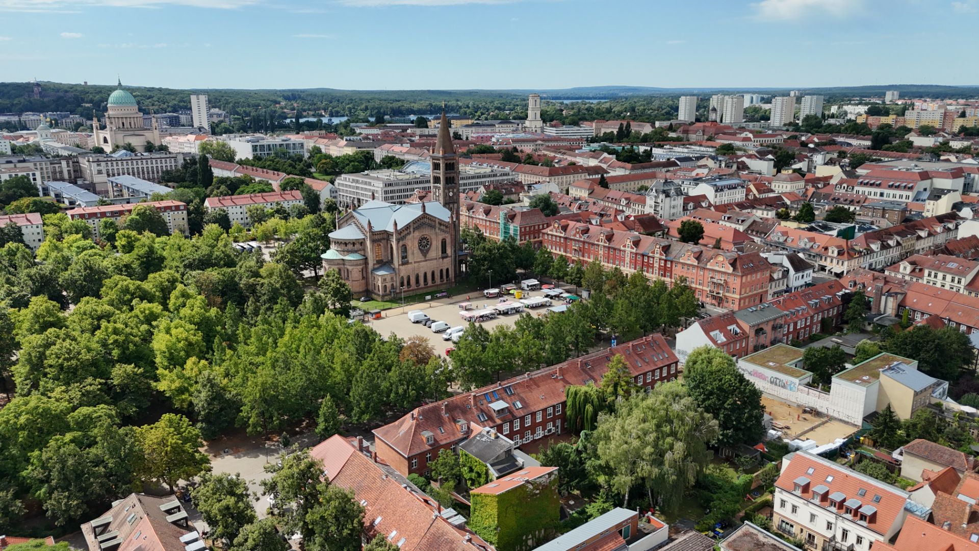 Luftaufnahme einer Stadt mit Kirche, vielen Bäumen und roten Dächern.