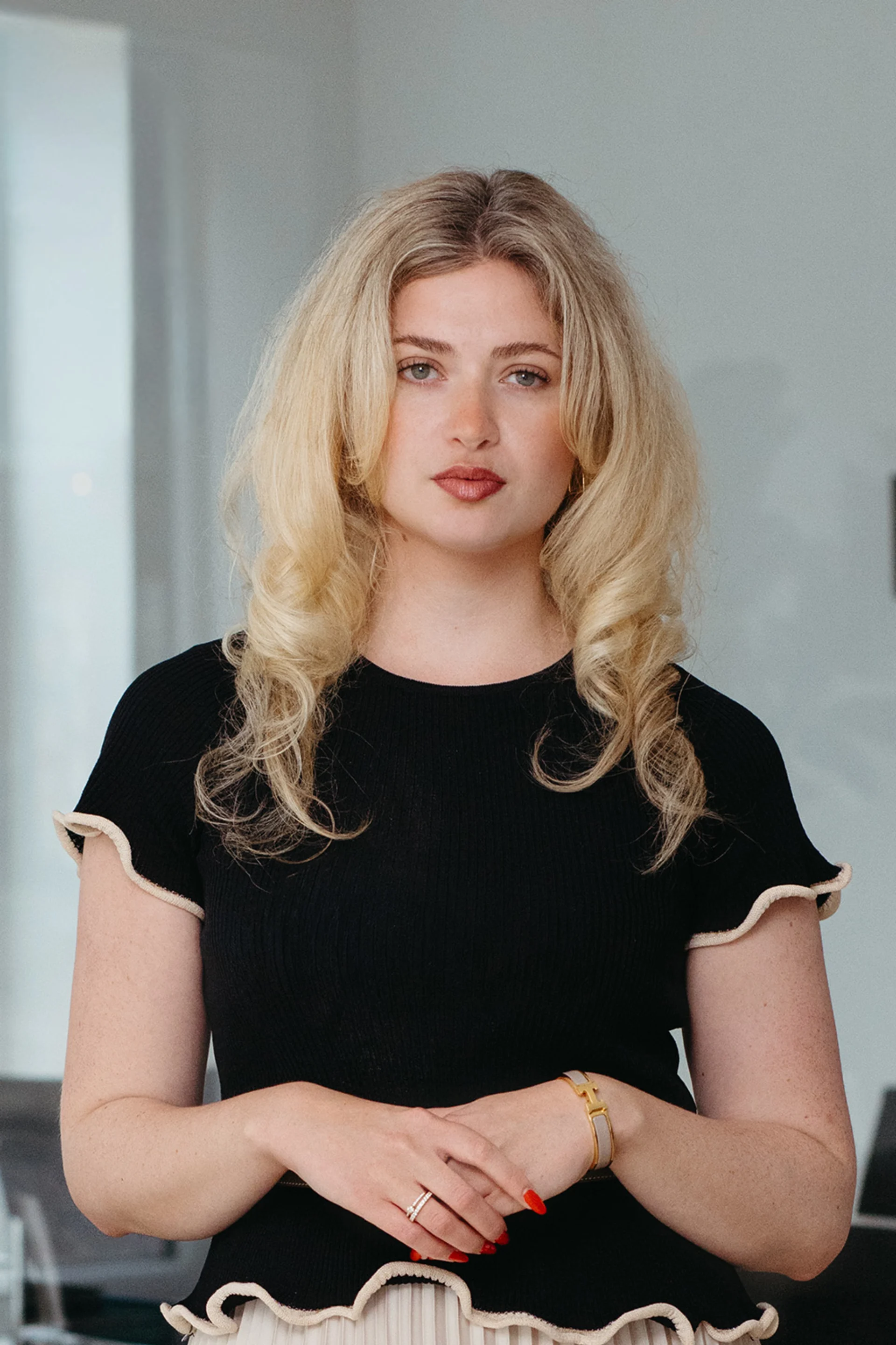 Eine lächelnde Frau mit langen, blonden Haaren trägt einen beigen Blazer und ein schwarzes Shirt.