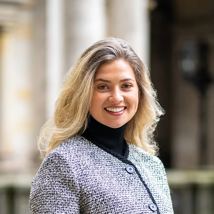 Eine lächelnde Frau mit langen, blonden Haaren trägt einen beigen Blazer und ein schwarzes Shirt.