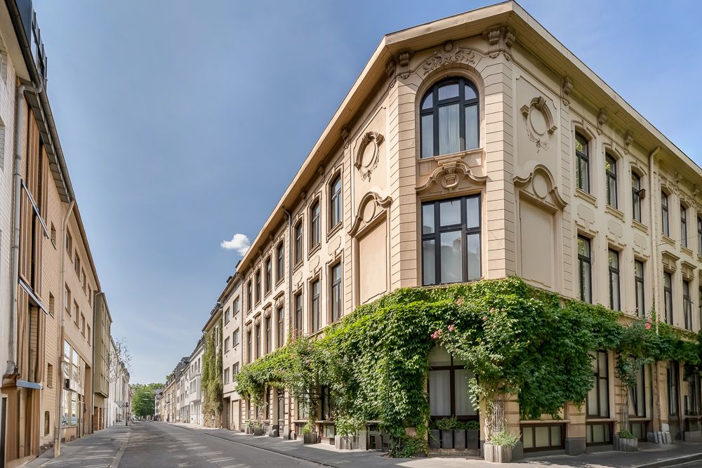 Eckhaus mit großen Fenstern und Fassadenbegrünung an einer ruhigen Straße.
