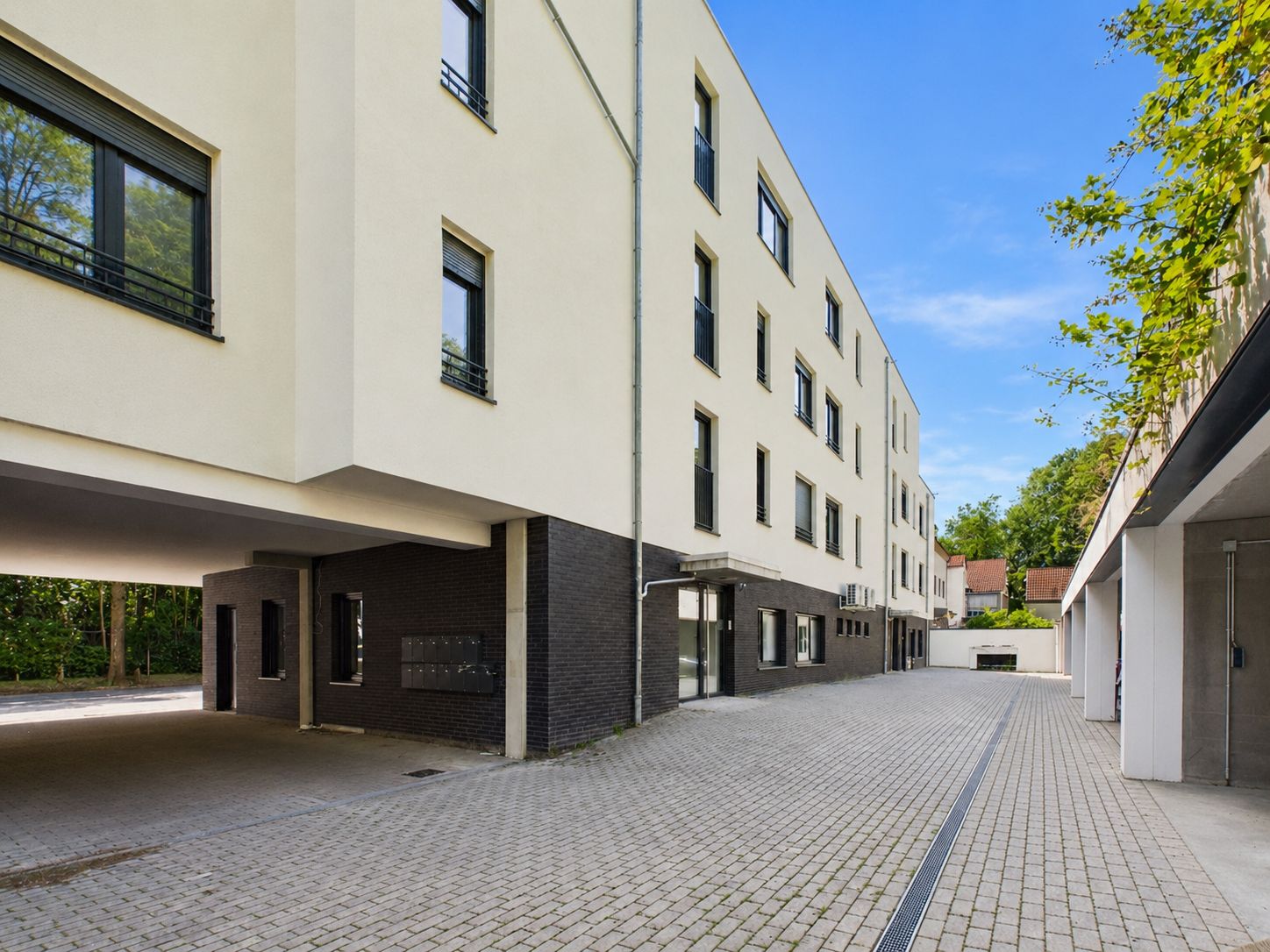 Moderner Wohnhauskomplex mit mehreren Fenstern und gepflastertem Innenhof.