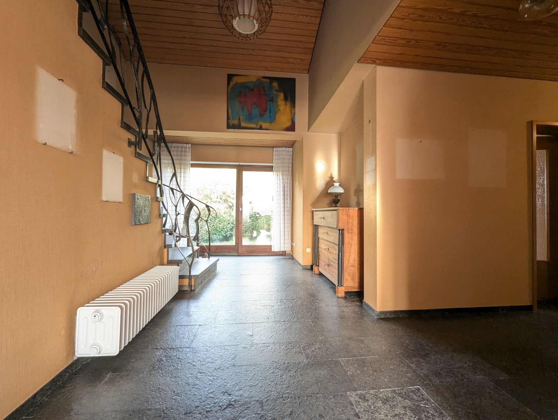Heller Flur mit Treppe, Kommode, Fenster und Blick auf Garten.