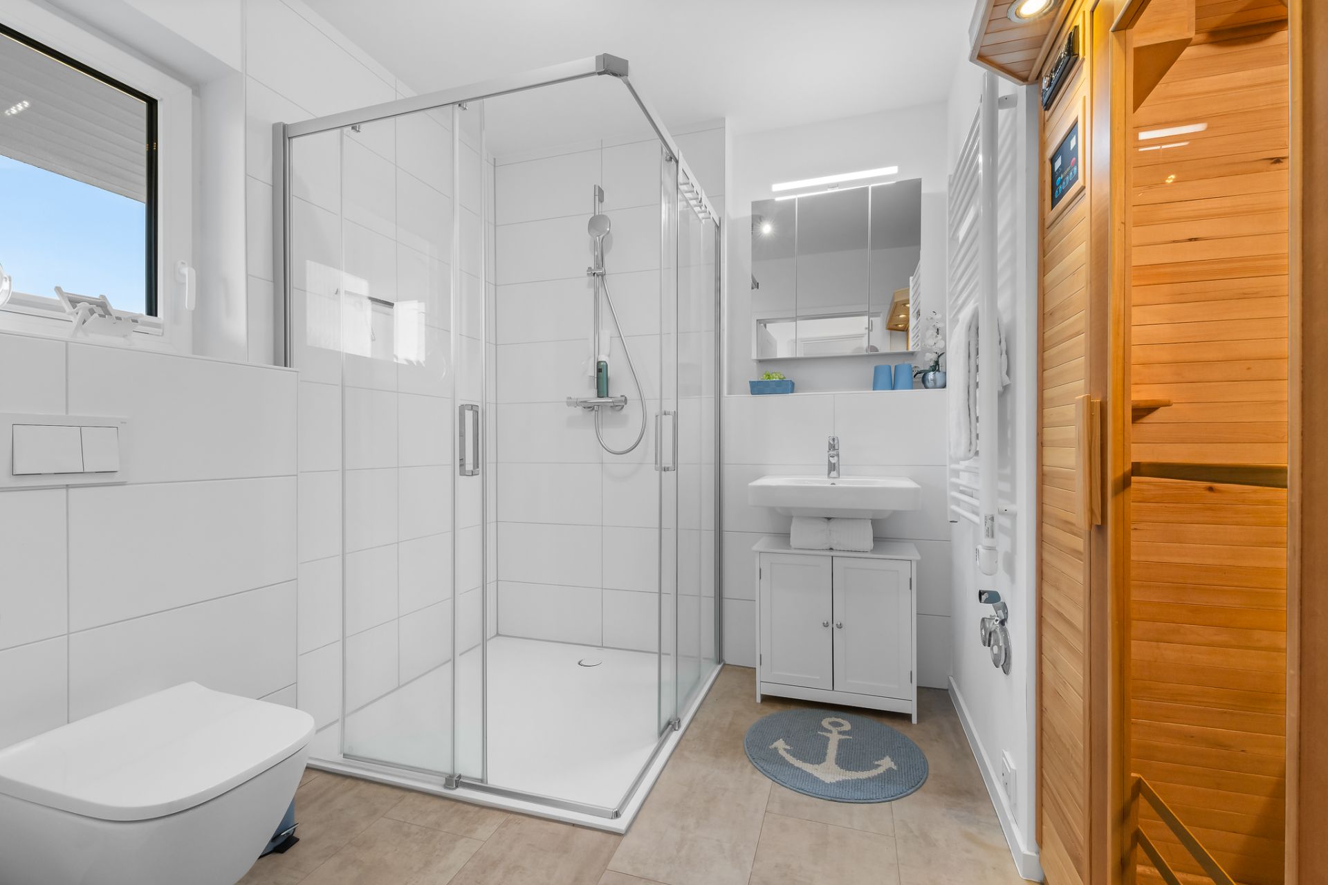 Modernes Badezimmer mit Dusche, WC, Waschbecken, Spiegel und einer Sauna rechts.
