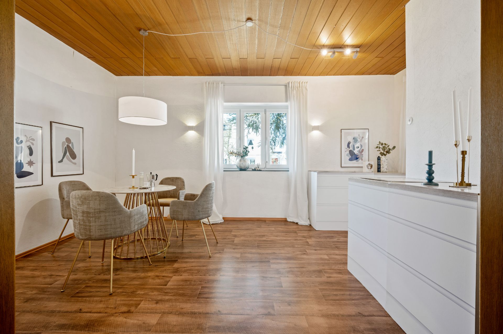Heller Essbereich mit rundem Tisch, vier Stühlen, Holzdecke und großem Fenster.