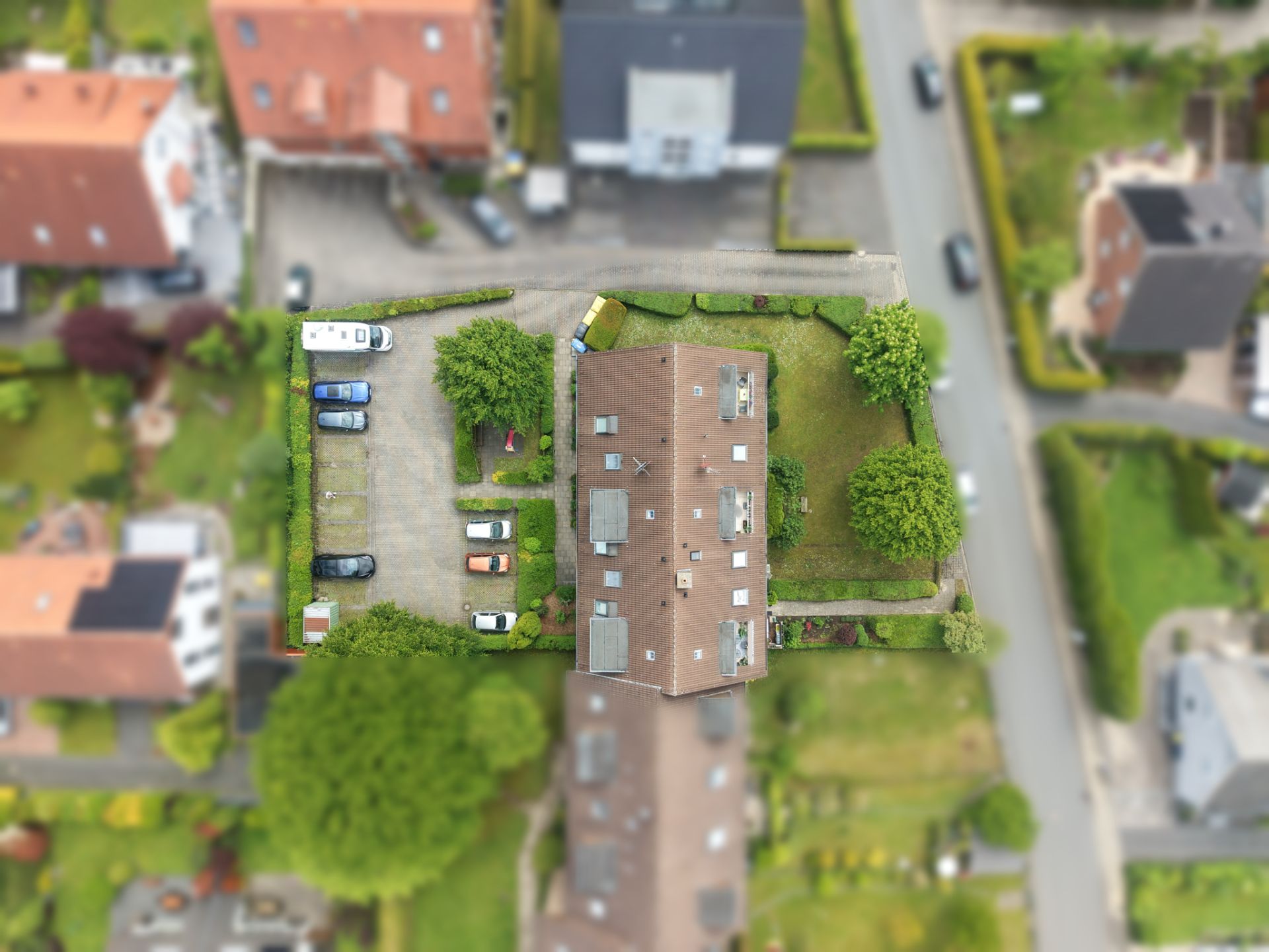 Luftaufnahme eines Wohnhauses mit Garten, Parkplatz und umgebenden Bäumen.