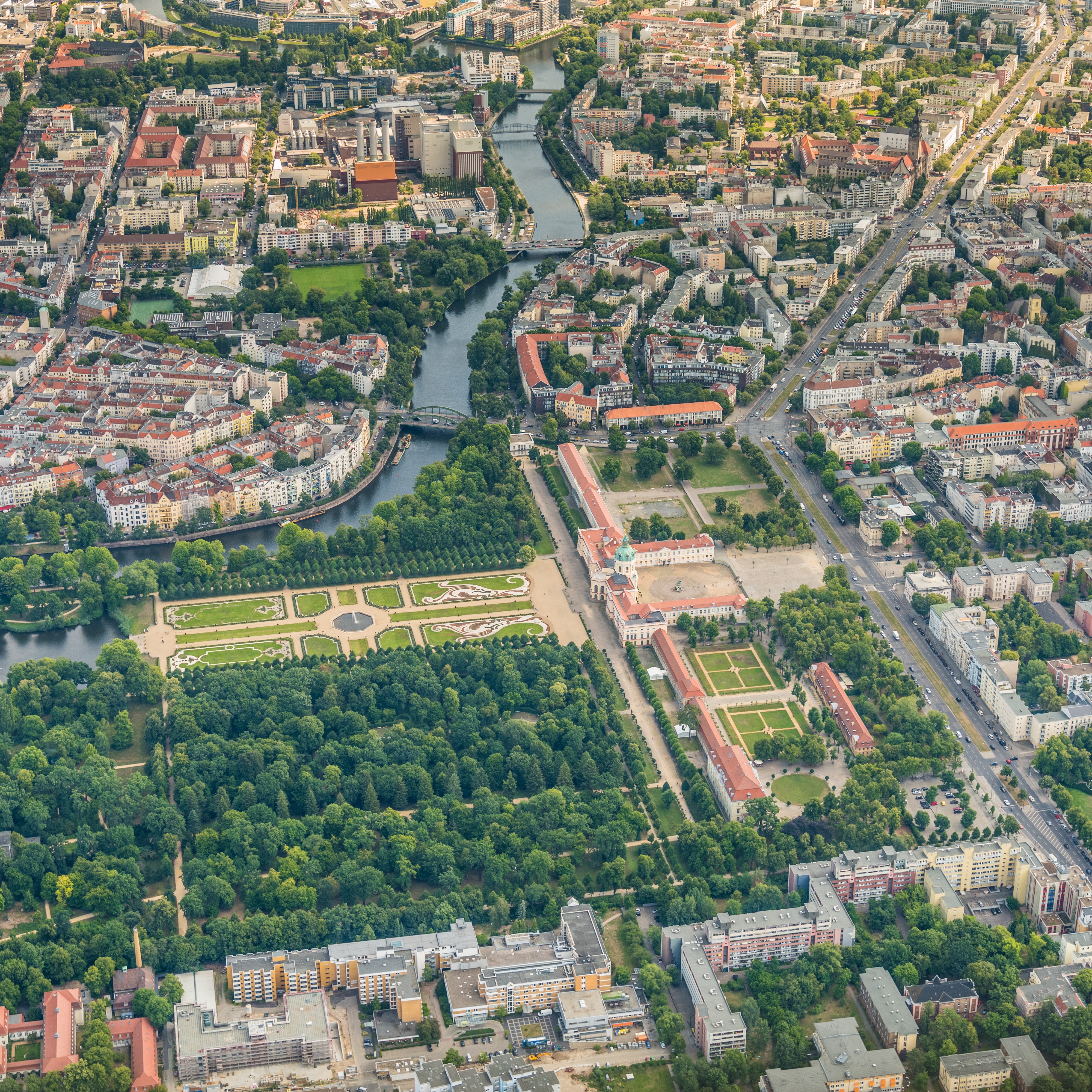 Luftaufnahme einer Stadt mit vielen Gebäuden, Parks und einem Fluss in der Mitte.