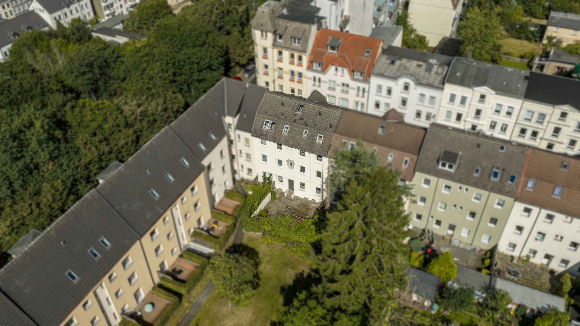 Luftaufnahme von mehreren Wohnhäusern mit begrünten Hinterhöfen und Gärten.