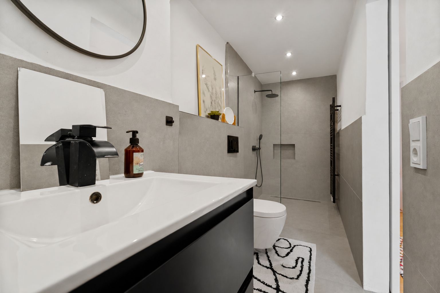 Modernes Badezimmer mit Waschbecken, Spiegel, Toilette und begehbarer Dusche.