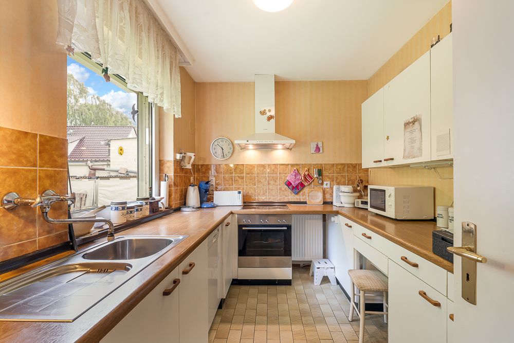 Helle Küche mit Herd, Spüle, Mikrowelle und Fenster zur Straße.