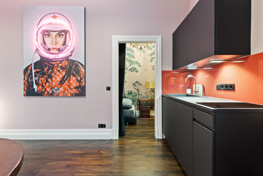 Moderne Küche mit roten Fliesen und großem Bild einer Person im Raumanzug an der Wand.