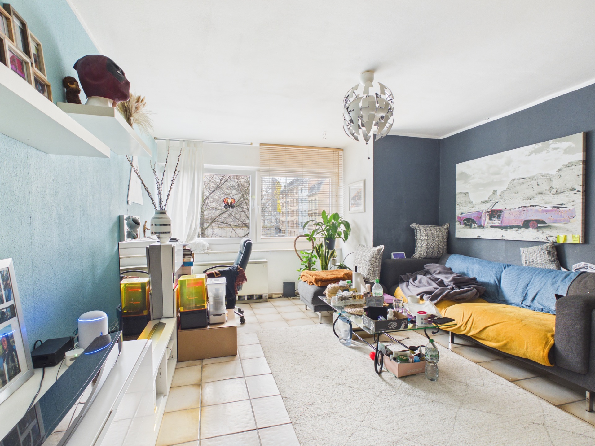 Helles Wohnzimmer mit Sofa, Glastisch, Pflanze und großem Fenster.