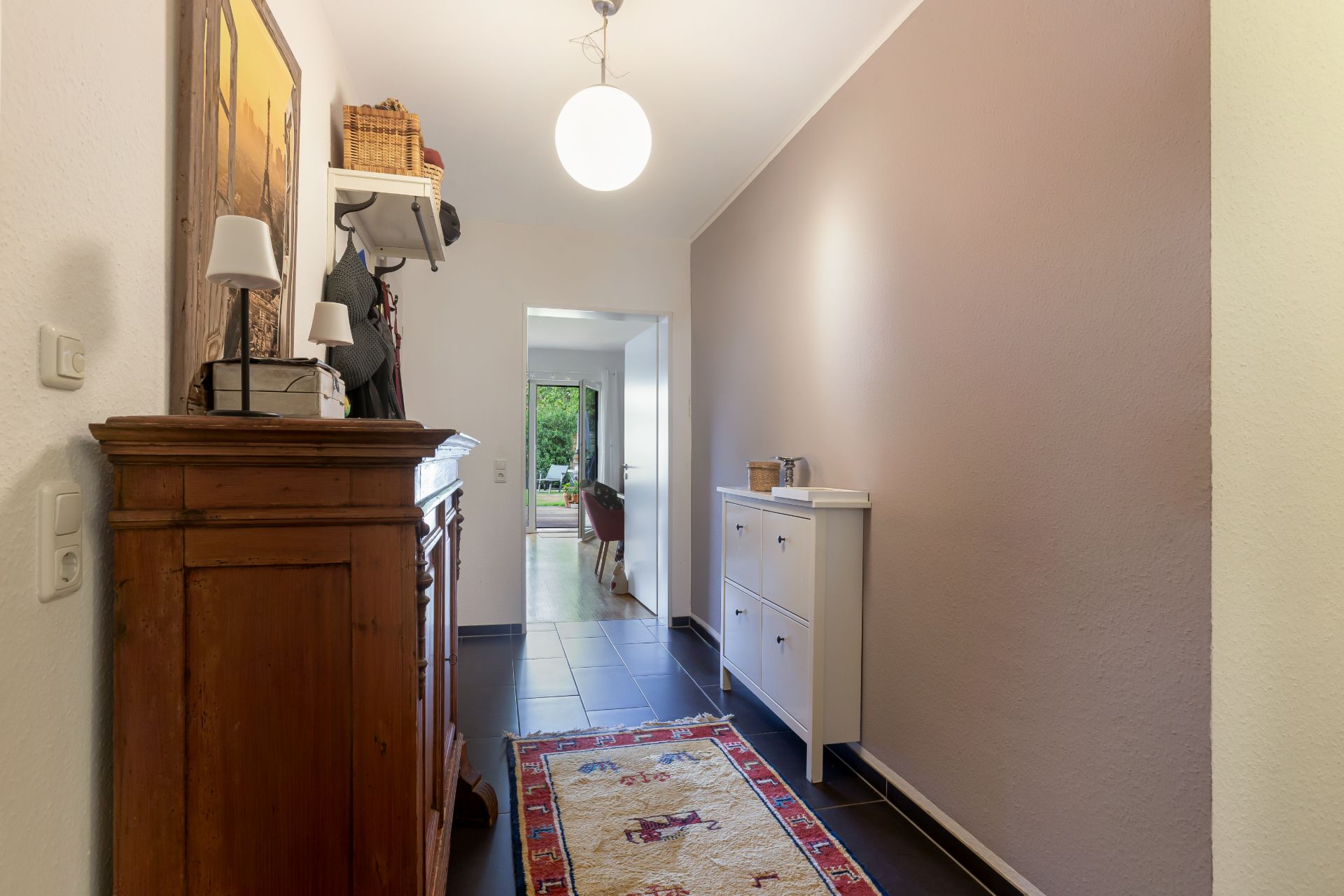 Flur mit Teppich, Holzkommode, Sideboard und heller Wandfarbe in einem Wohnhaus.