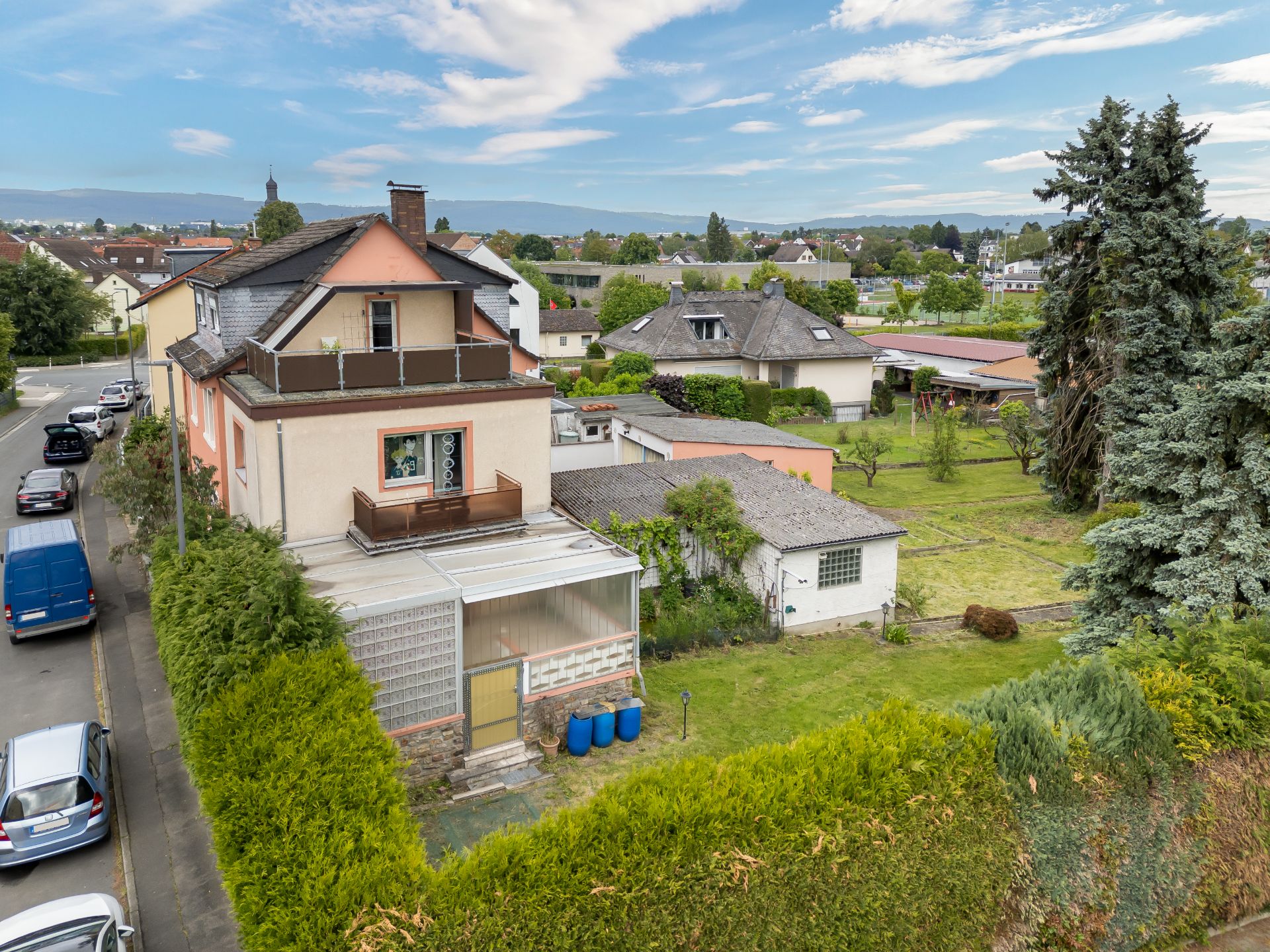Zweistöckiges Wohnhaus mit großem Garten, Nebengebäude und Balkon in ruhiger Wohngegend.