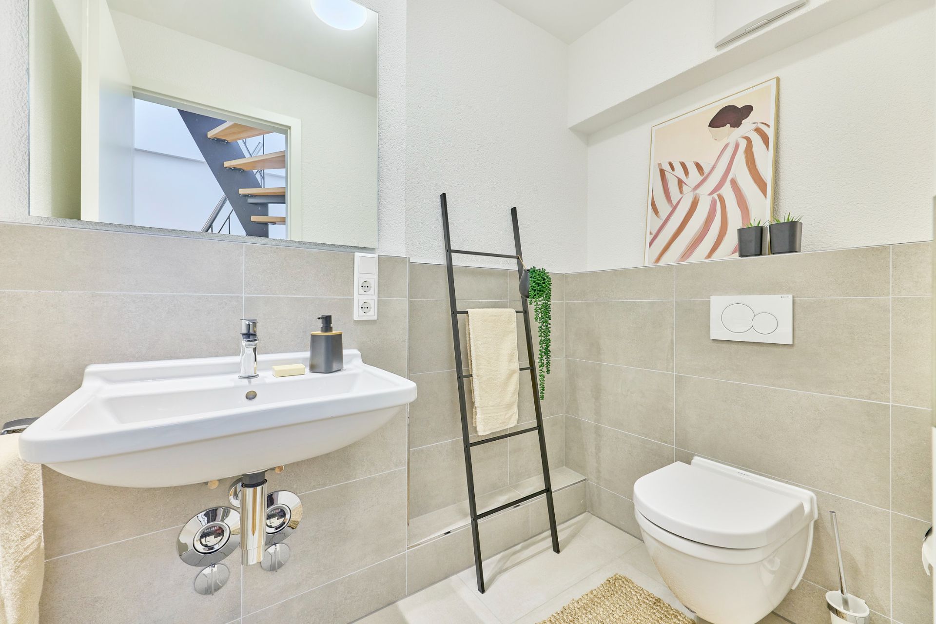 Modernes Badezimmer mit Waschbecken, Toilette, Spiegel und Handtuchleiter.
