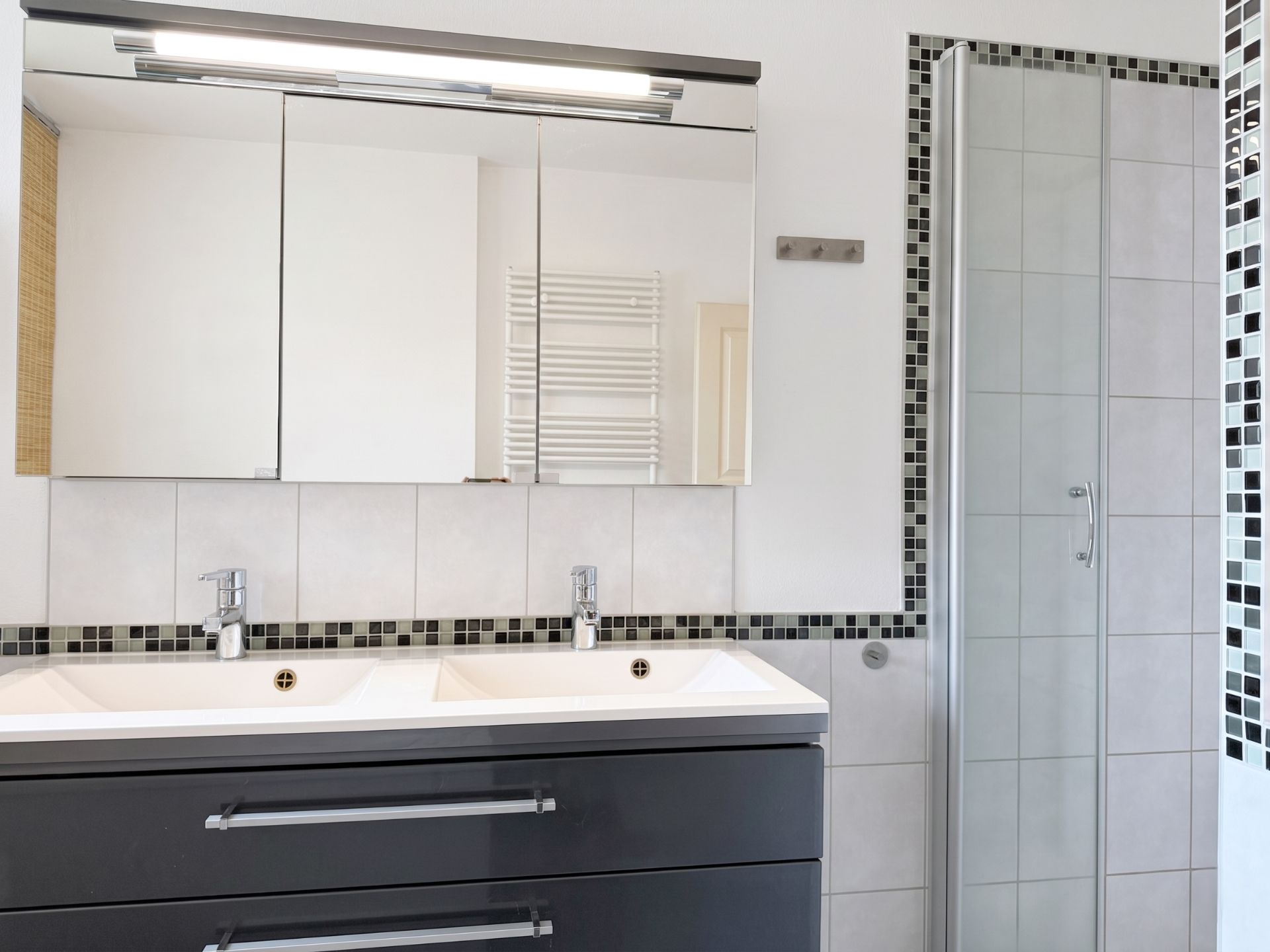 Modernes Badezimmer mit Doppelwaschbecken, großem Spiegel und verglaster Dusche.