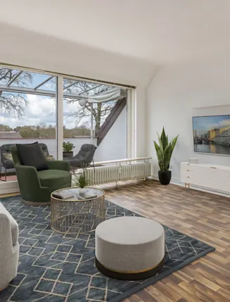 Helles Wohnzimmer mit Sofa, Sessel, Teppich, Fernseher und Zugang zu einer Terrasse mit Sitzmöbeln.