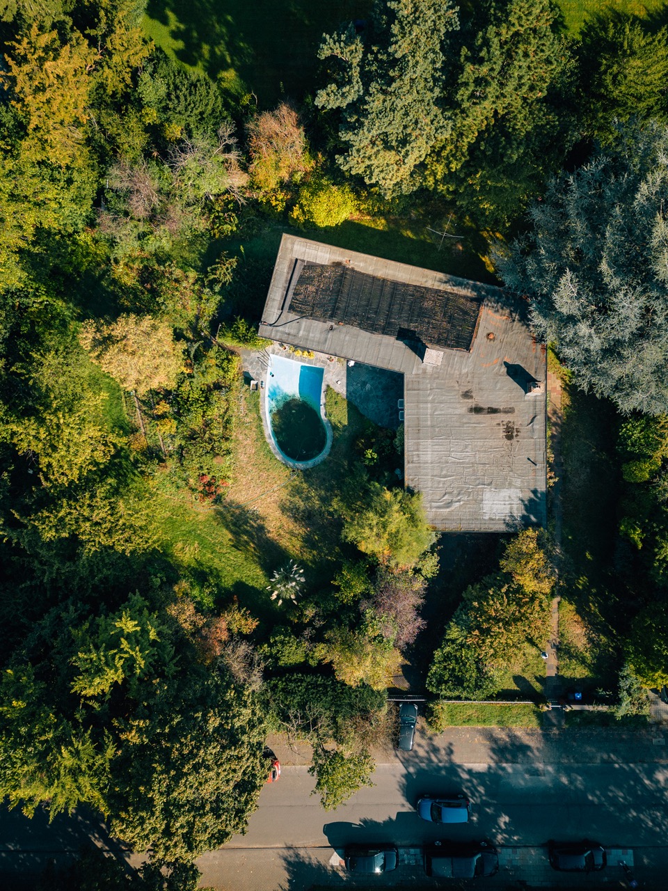 Luftaufnahme eines Wohnhauses mit Garten, Pool und umliegenden Bäumen.