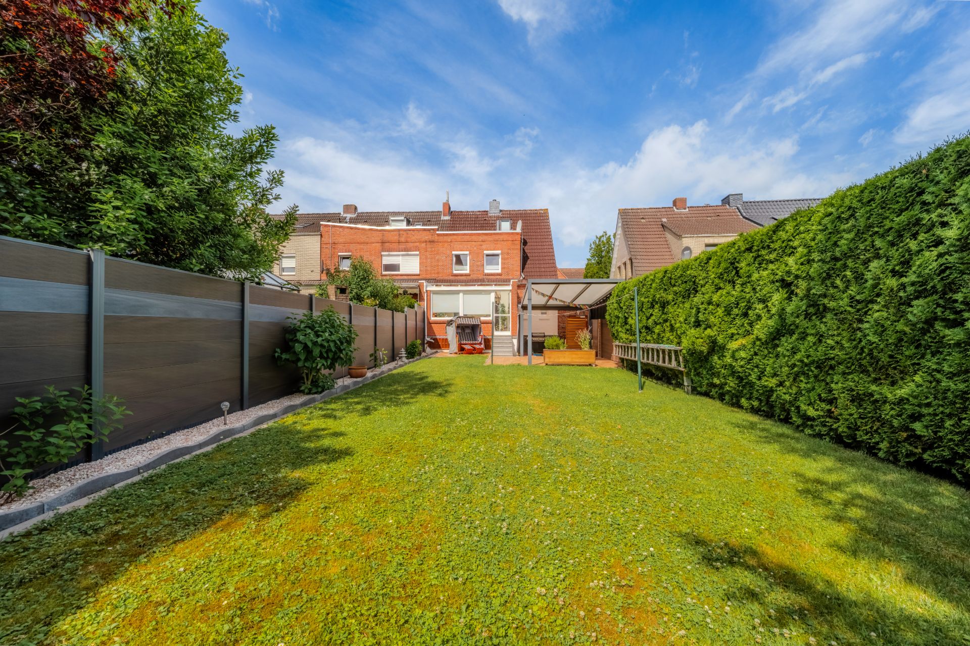 Gepflegter Garten mit Rasenfläche, Terrasse, Sichtschutzzaun und angrenzendem Wohnhaus.