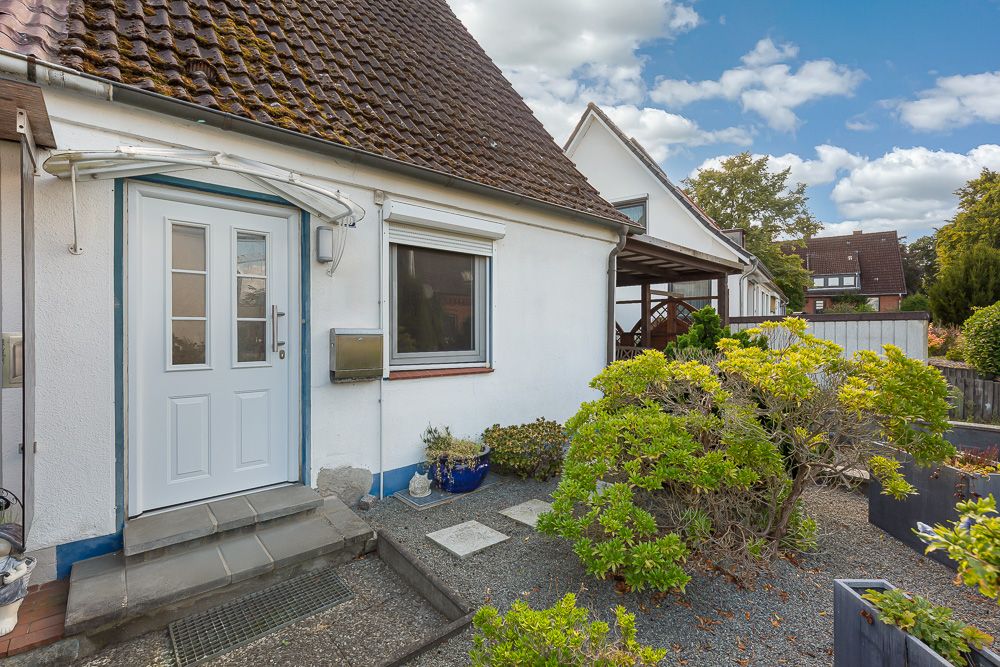 Eingangsbereich eines Einfamilienhauses mit Vorgarten und weißer Tür.