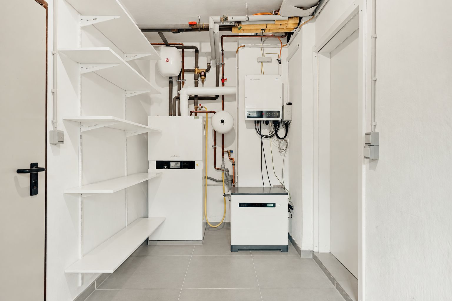 Hauswirtschaftsraum mit Regalen, Heizung und technischen Geräten an der Wand.